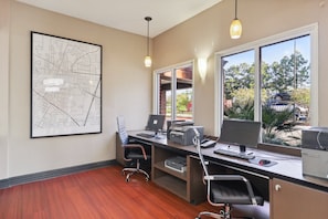 A modern office with a large desk, two monitors, a printer, and a map on the wall.