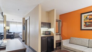 A hotel room with a kitchenette, a sofa, a dining table, and a TV.