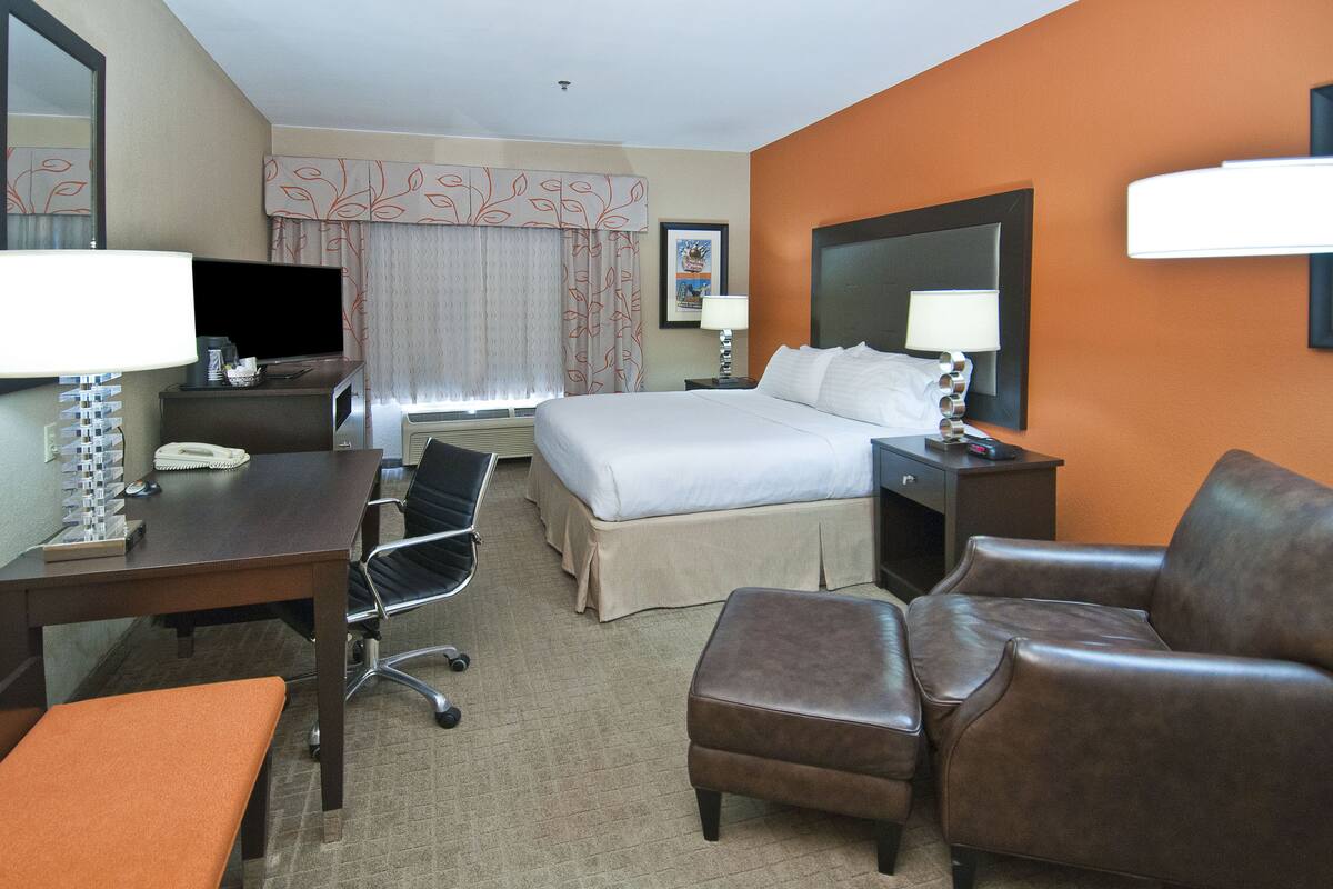 A hotel room with a bed, desk, chair, and a small table.