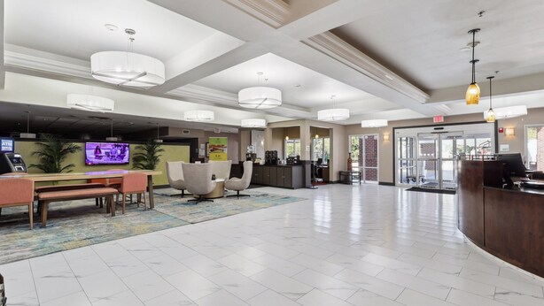 A spacious lobby with a reception desk, seating area, and a television screen.