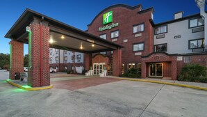 Un hôtel Holiday Inn avec une façade en briques, une entrée couverte et un parking.