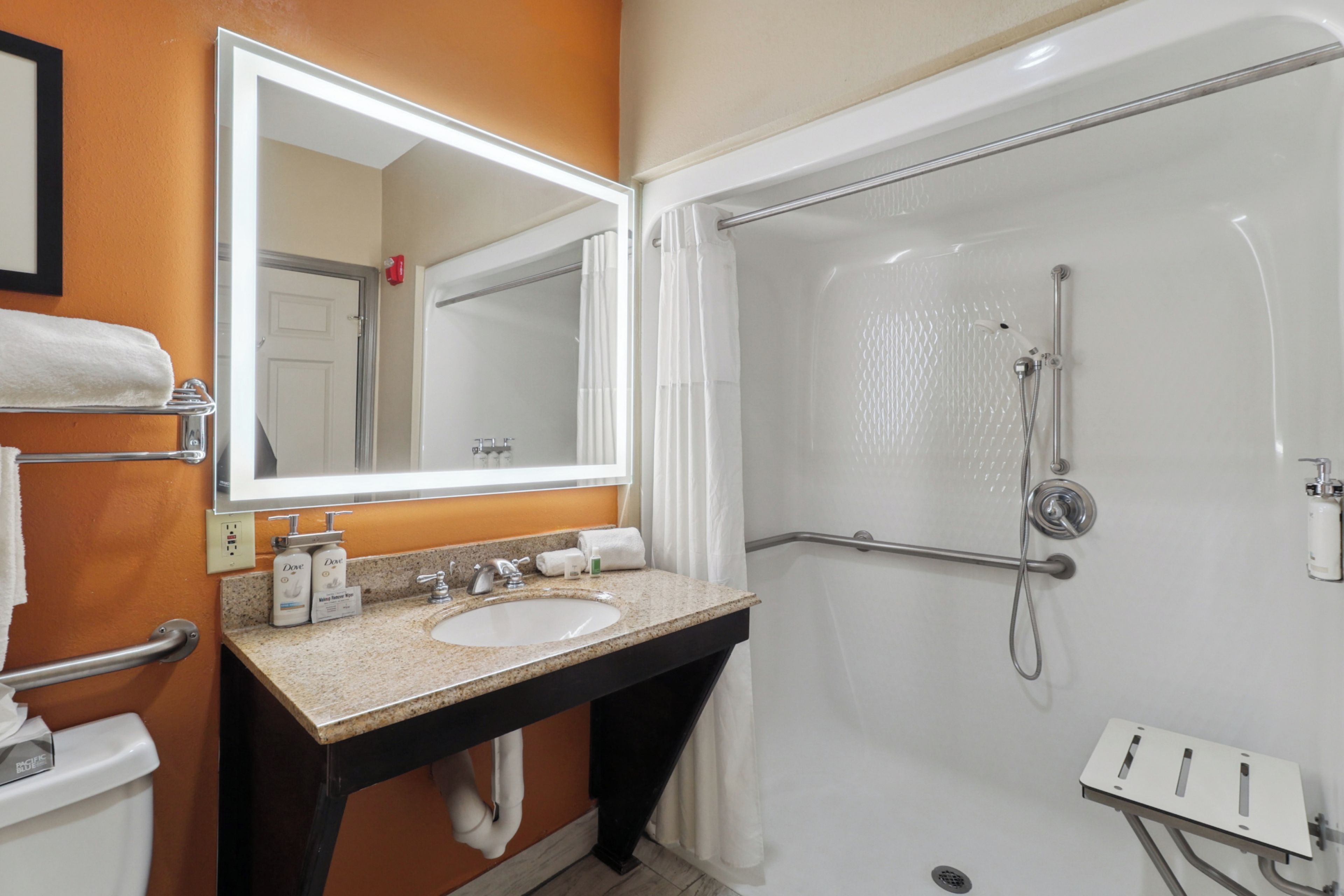 A bathroom with a sink, mirror, and shower.