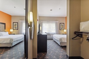 Habitación de hotel con dos camas, un escritorio y un espejo.
