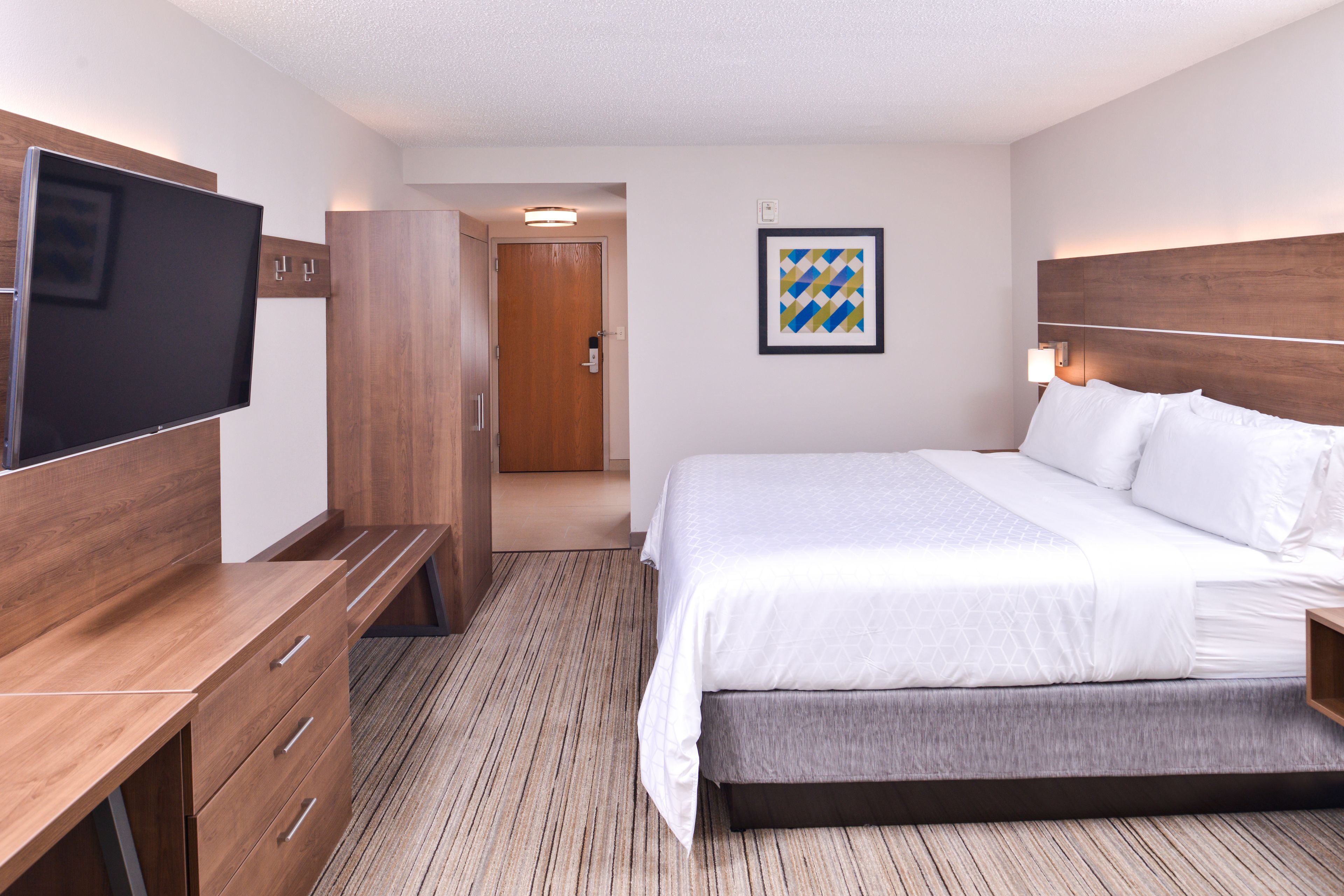 Una habitación de hotel con cama, televisión, escritorio y armario.