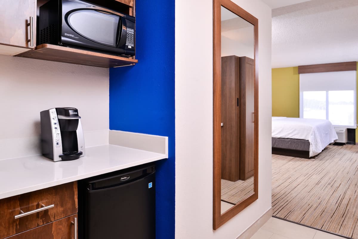 Une chambre d’hôtel de taille réduite équipée d’une kitchenette, d’un four à micro-ondes, d’une machine à café et d’un lit.