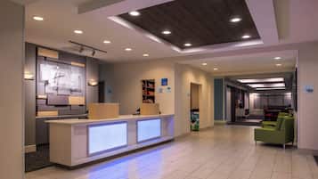 A modern reception area with a reception desk, a waiting area with green chairs, and a business center.