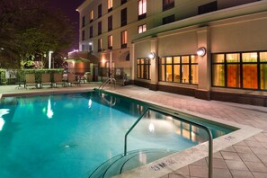 A swimming pool with a clear edge, surrounded by a paved deck and a building with multiple windows. - Holiday Inn Express Hotel & Suites Tampa-Anderson Rd/Veteran by IHG (Tampa)