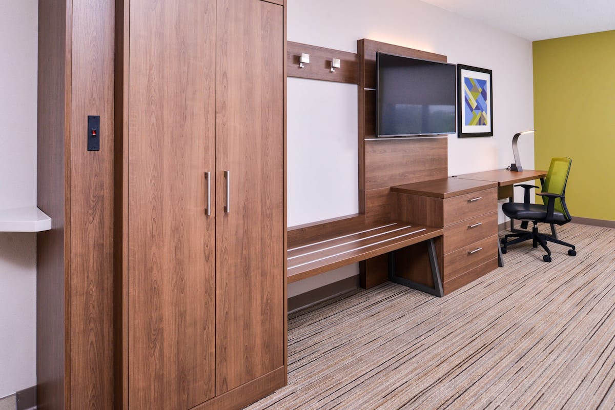 Un espace de bureau moderne comprenant un bureau en bois, une chaise, un téléviseur et un meuble de rangement.