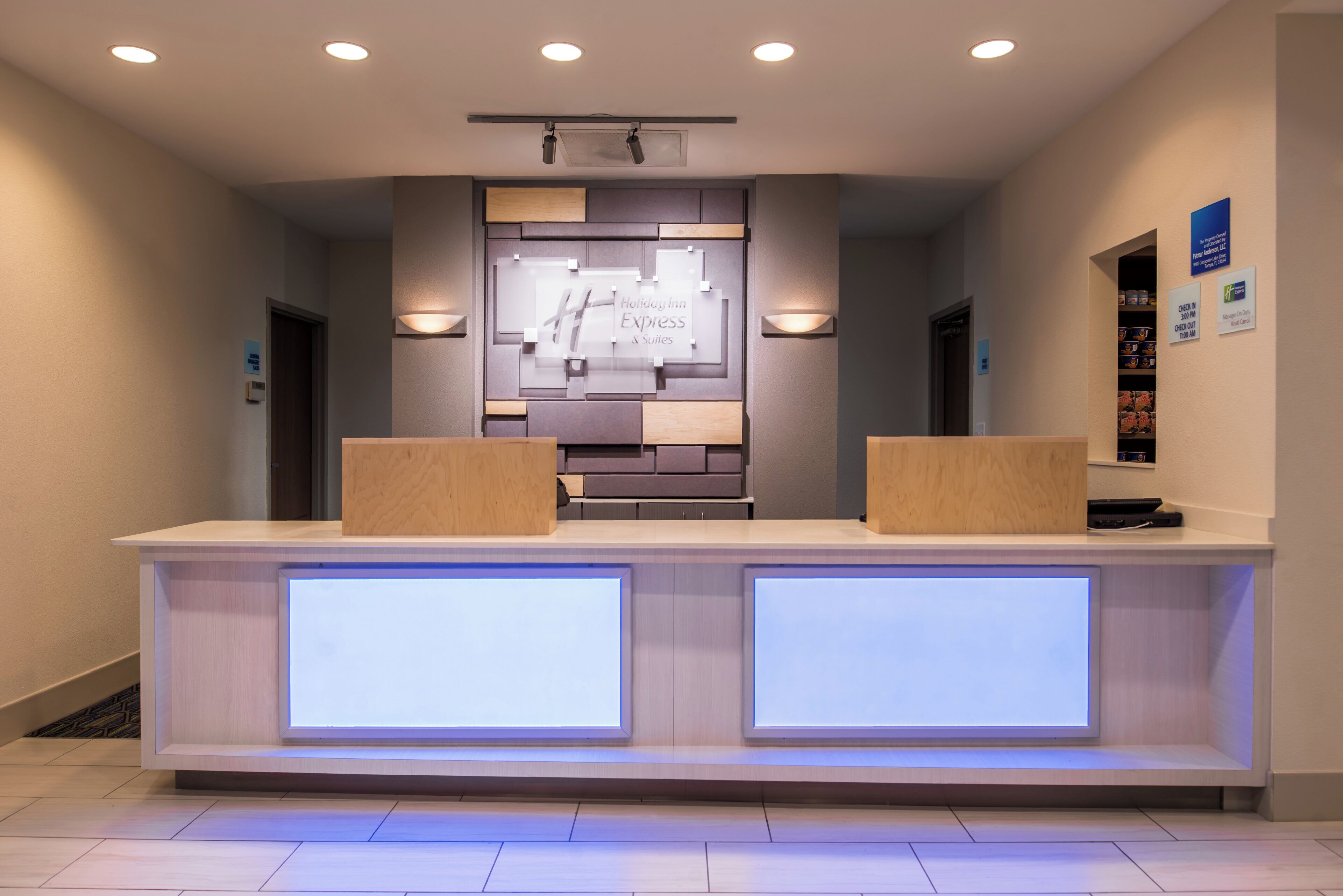 A reception desk with a digital display, a wooden counter, and a wall-mounted sign.