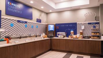 A breakfast area with a buffet setup, including labeled food stations and a coffee machine.