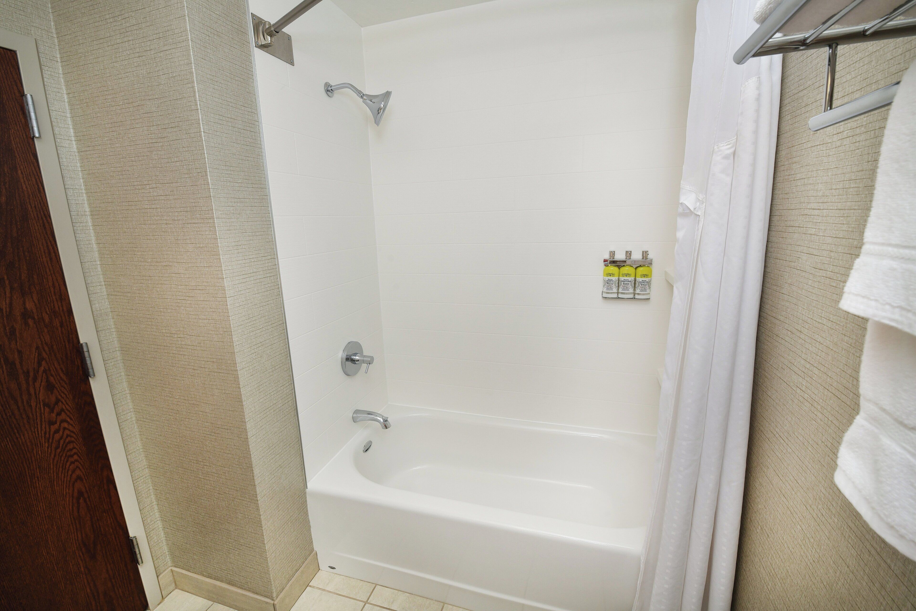 A bathroom with a bathtub, a shower, and a towel rack.