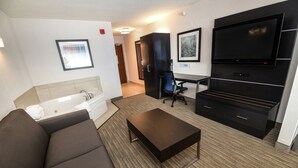 Una habitación de hotel moderna con sofá, televisión de pantalla plana, escritorio y ventana grande.