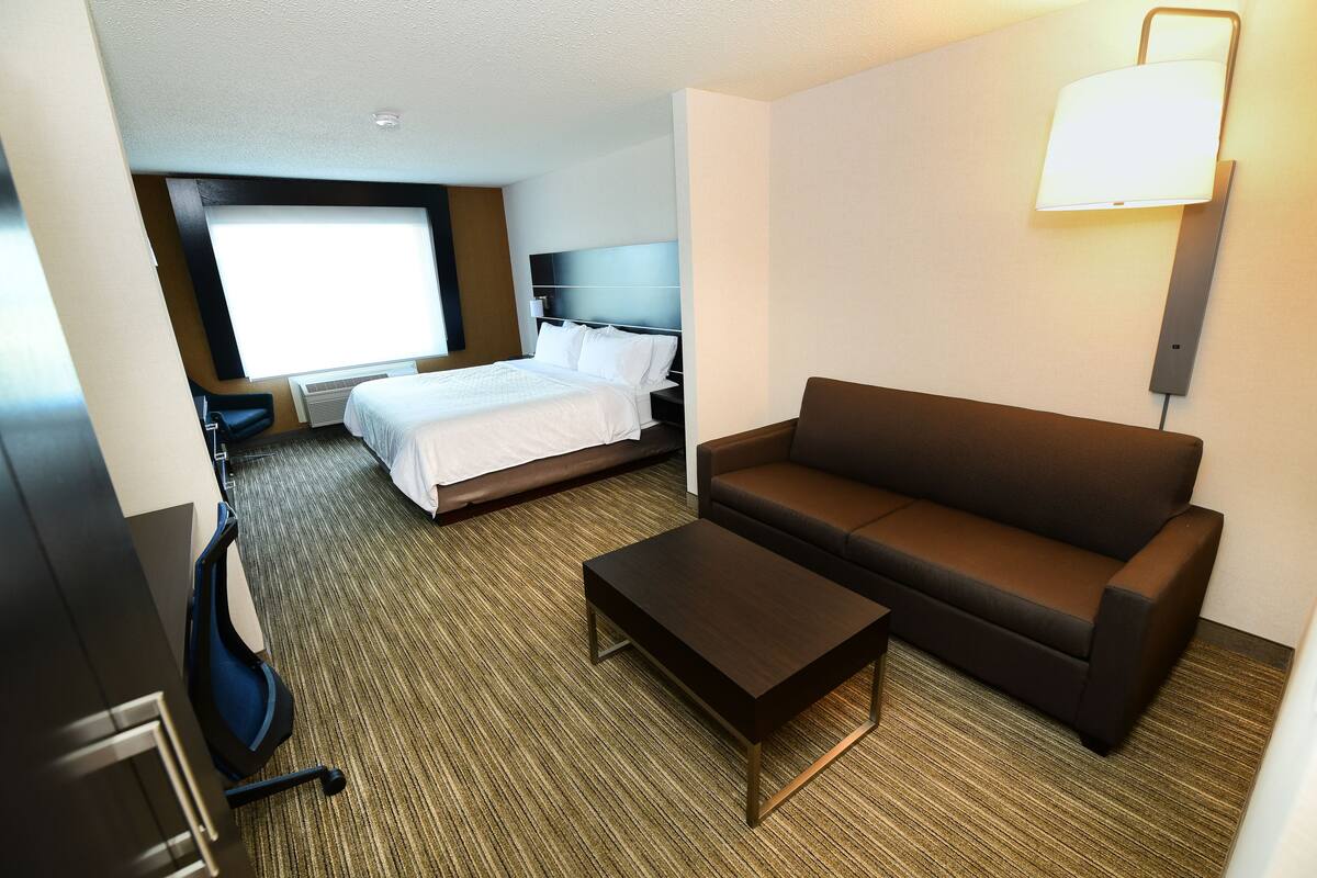 Une chambre d’hôtel comprenant un lit, un canapé, une table basse et un bureau avec une chaise.