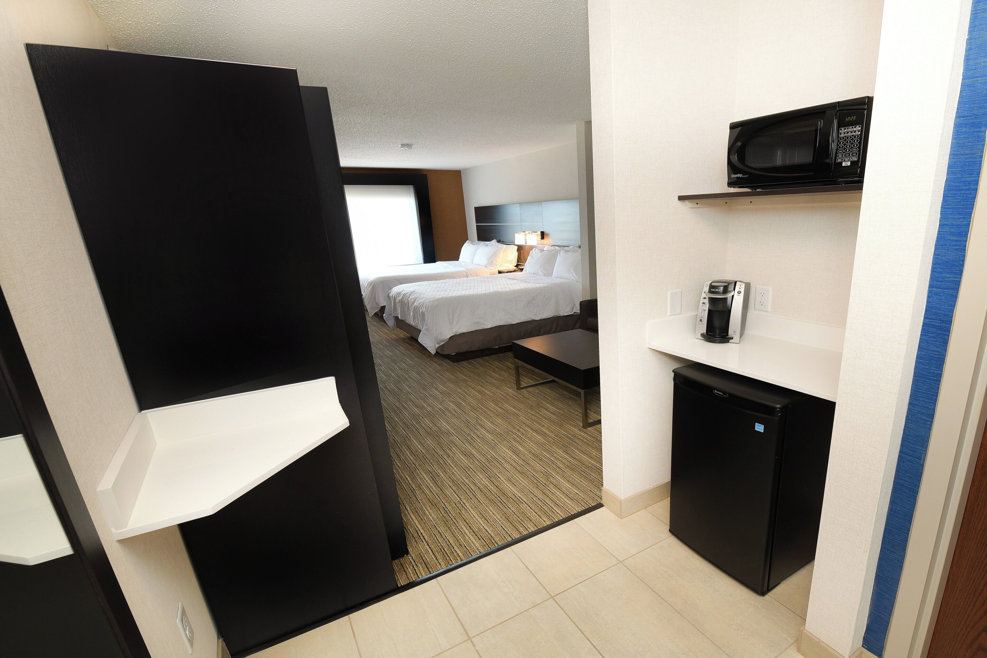 A hotel room with a bed, bedside table, and a minibar.