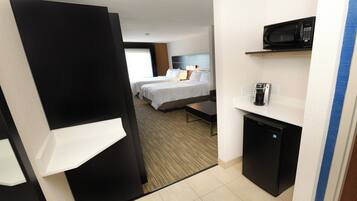 A hotel room with a bed, bedside table, and a minibar.