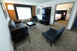 Una habitación de hotel con sofá, sillón, televisión y cama.