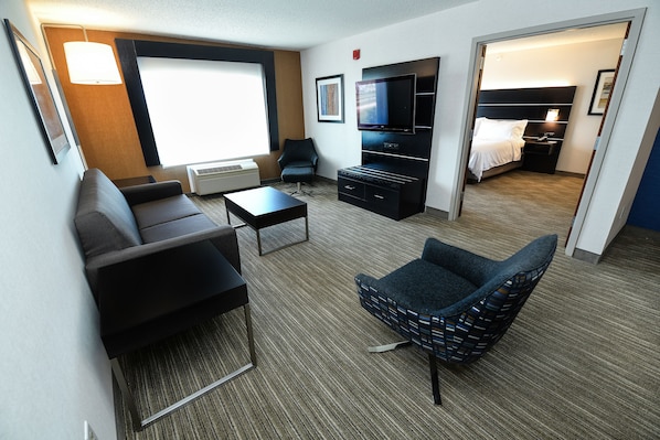 Une chambre d’hôtel avec un canapé, un fauteuil, une télévision et un lit.