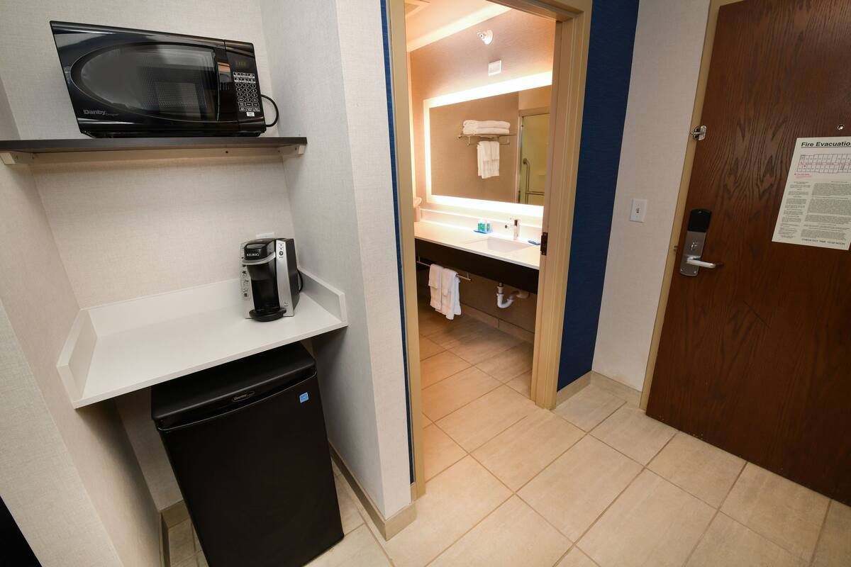 Une petite salle de bain d’hôtel équipée d’un four à micro-ondes, d’une machine à café et d’un lavabo.