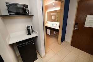 Une petite salle de bain d’hôtel équipée d’un four à micro-ondes, d’une machine à café et d’un lavabo.