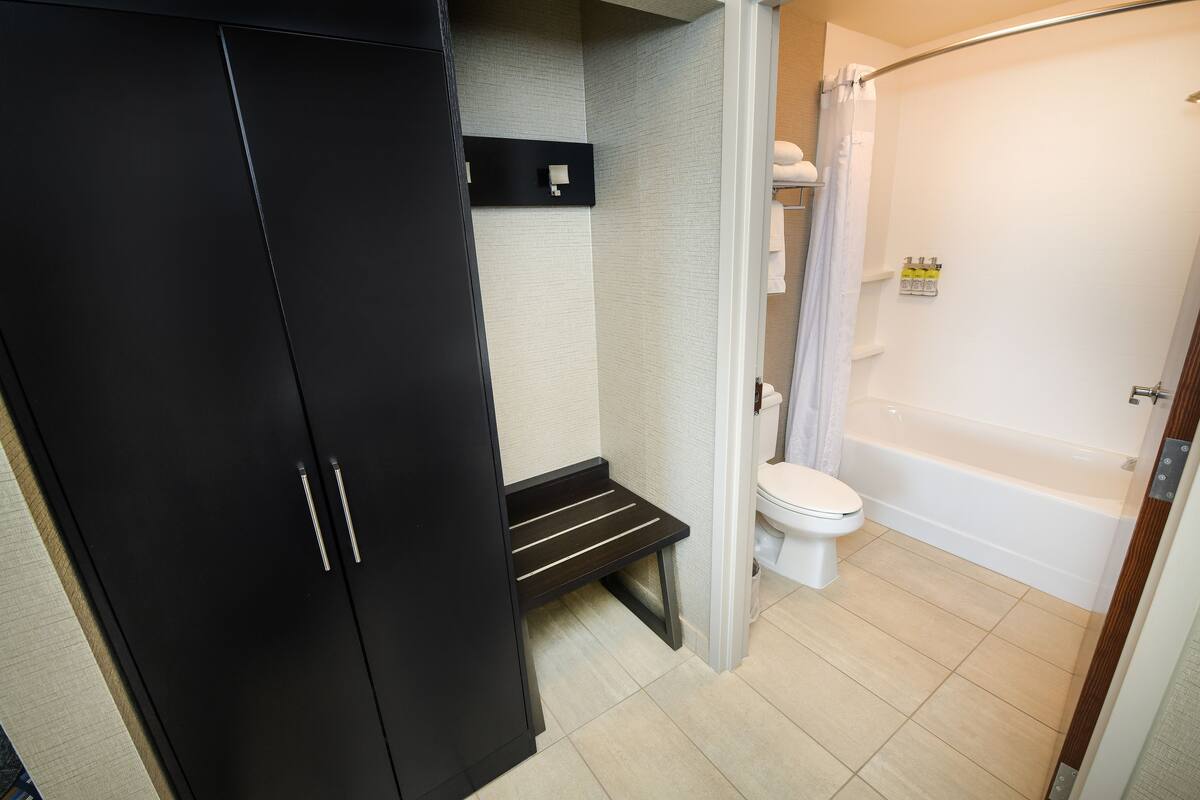 Une salle de bain avec des toilettes, une baignoire et un placard noir.
