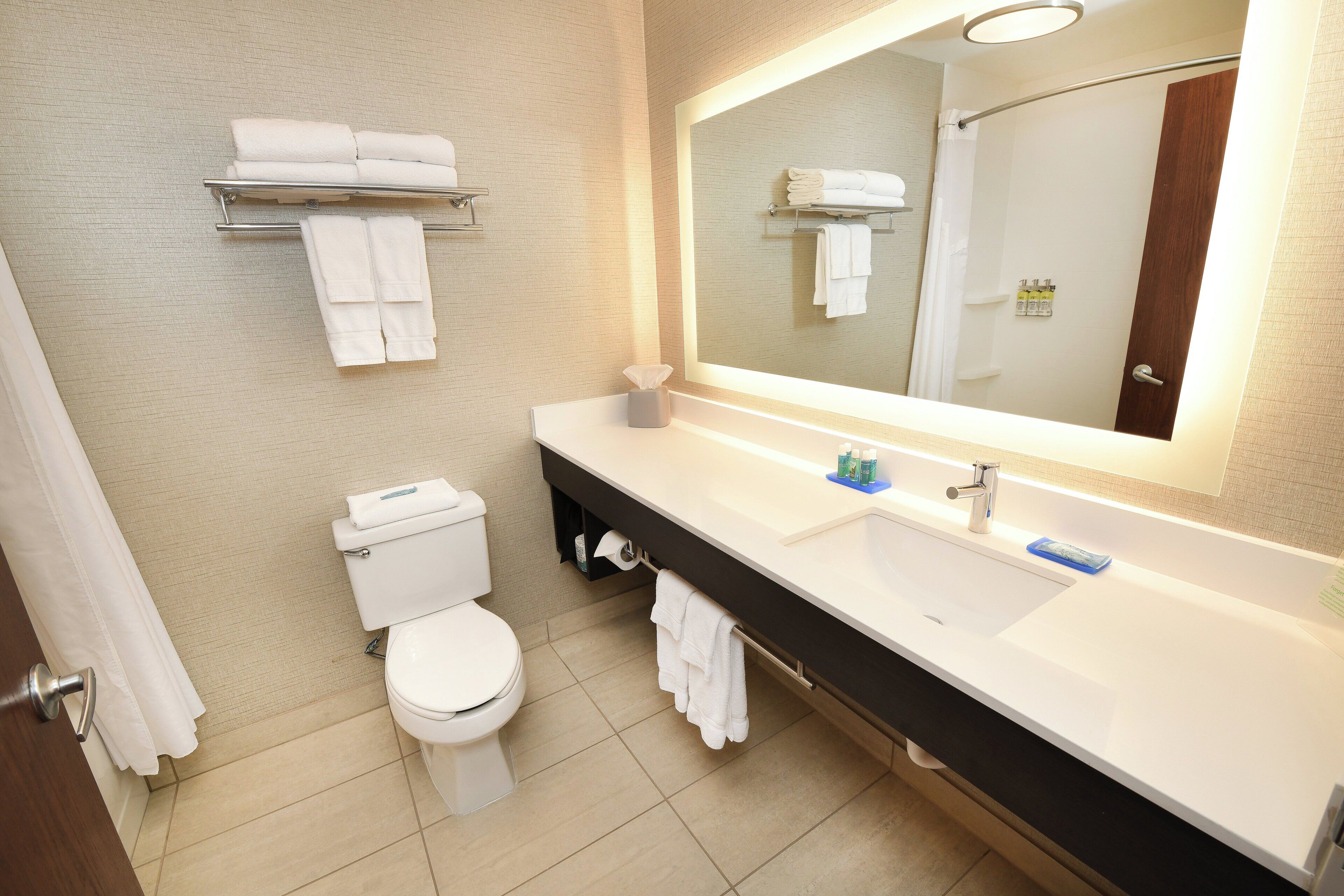 A modern bathroom with a toilet, sink, and mirror.
