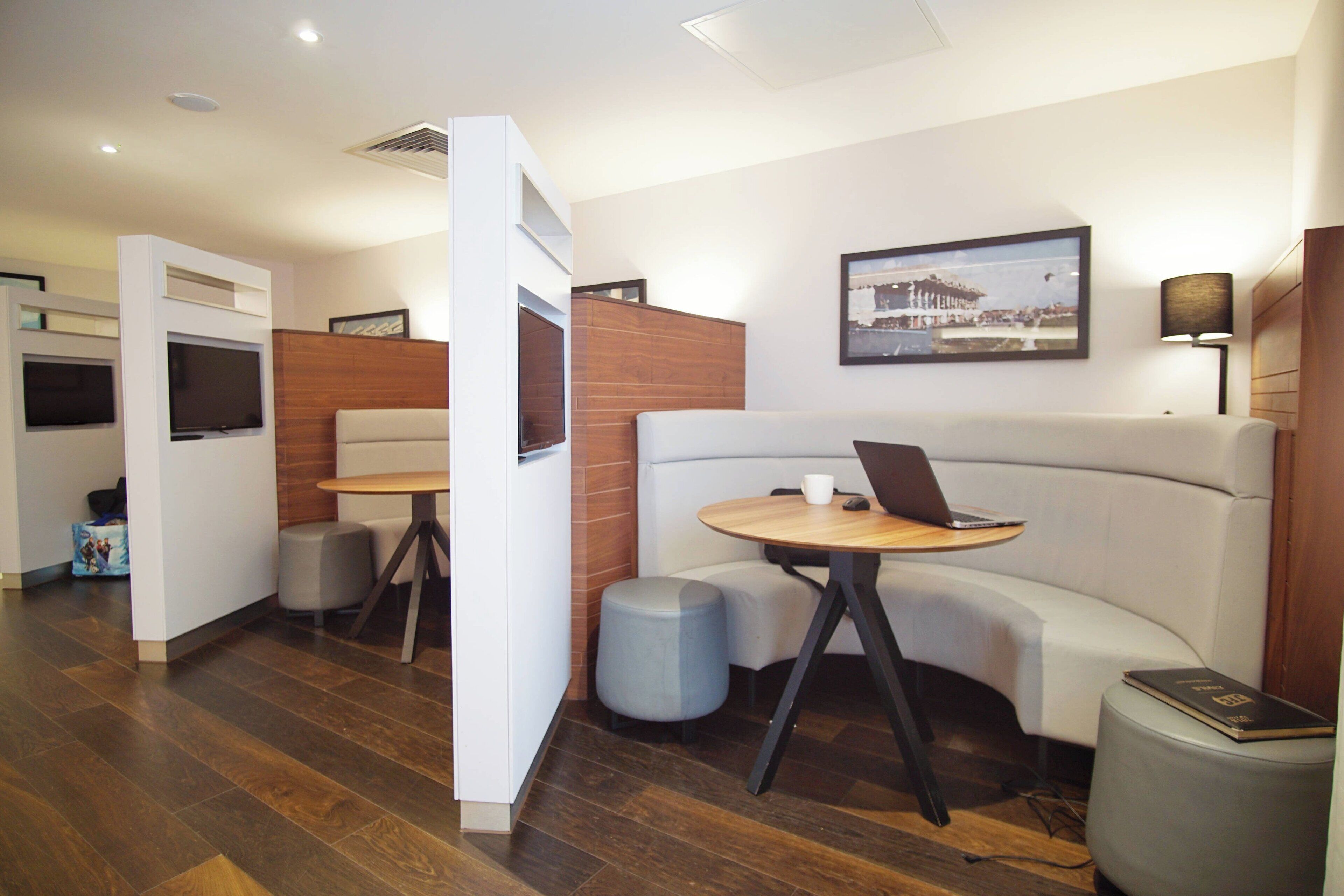 A modern hotel lobby with a seating area, a television, and a framed picture on the wall.
