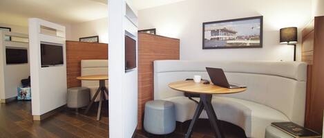 A modern hotel lobby with a seating area, a television, and a framed picture on the wall.