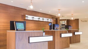 Een receptiegedeelte met houten lambrisering, een digitaal scherm, een koelkast en een plant.