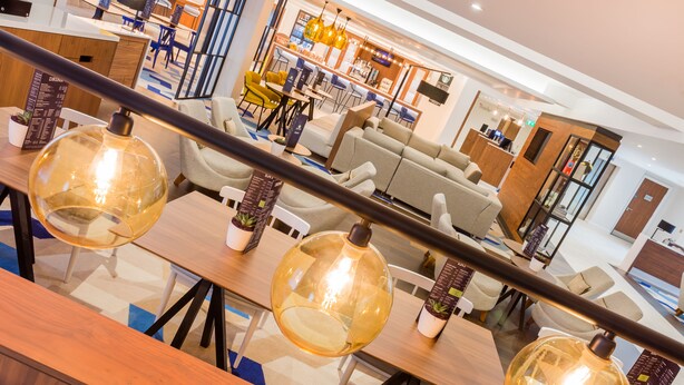 Een moderne hotellobby met een zithoek, een bar en een receptiebalie.