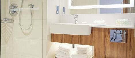 Un bagno moderno con doccia vetro, lavabo bianco e mobile vanitario in legno.