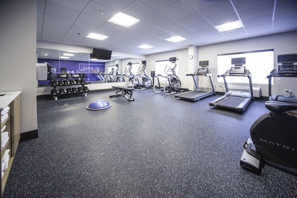 A gym with treadmills, elliptical machines, and free weights.