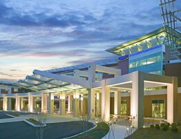 Un hotel moderno con un área exterior techada, ventanas amplias y un letrero que indica que es un hotel Marriott.
