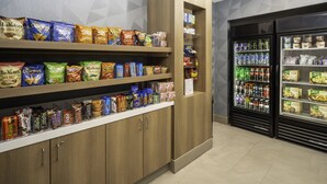 A snack and beverage display area with various packaged snacks and bottled drinks. - Holiday Inn Express Hotel & Suites Atlanta Johns Creek by IHG (Suwanee)