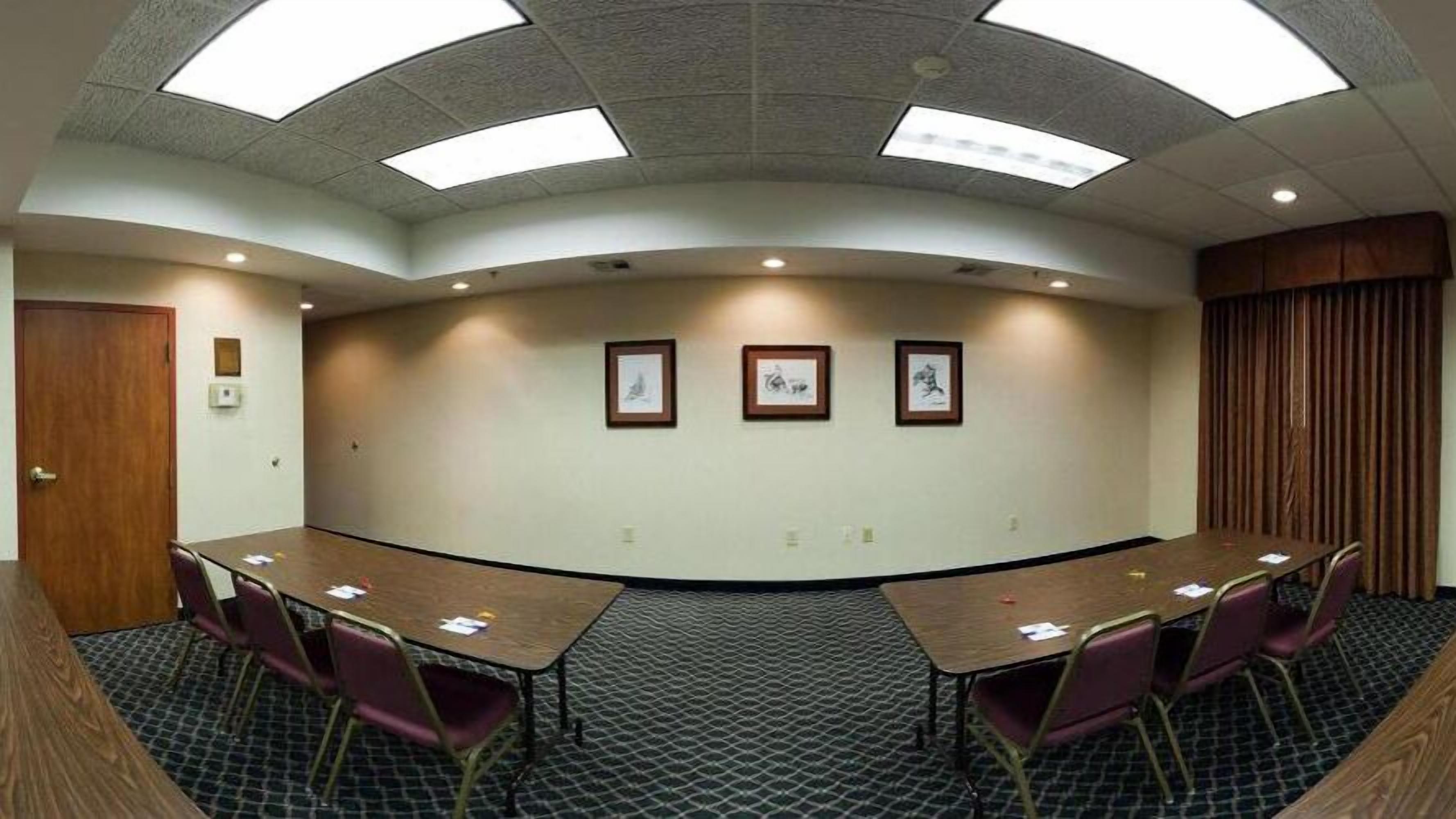 A conference room with a curved layout, equipped with a long table and several chairs, and framed artwork on the walls.