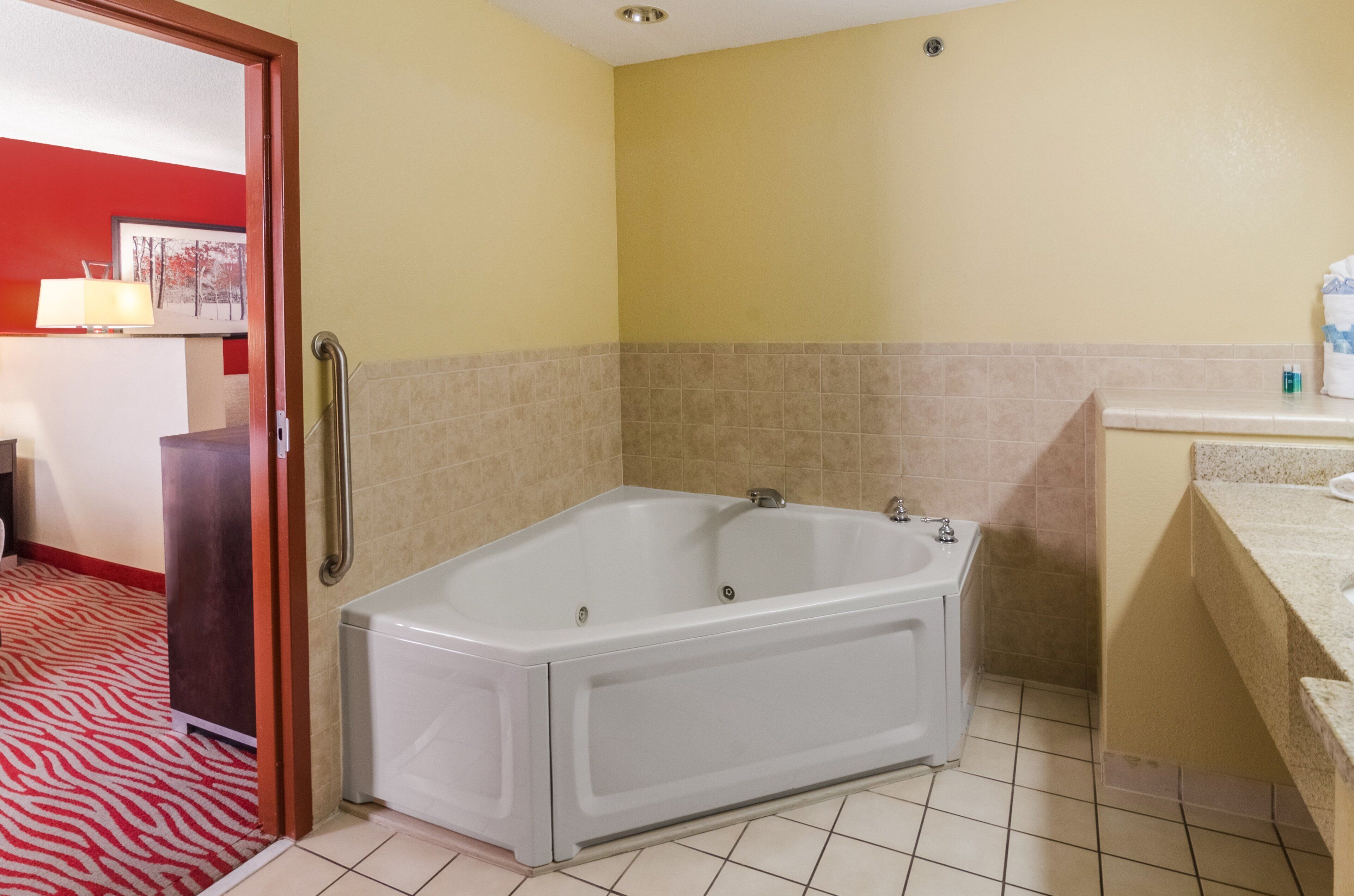 A bathroom with a large bathtub, a sink, and a mirror.