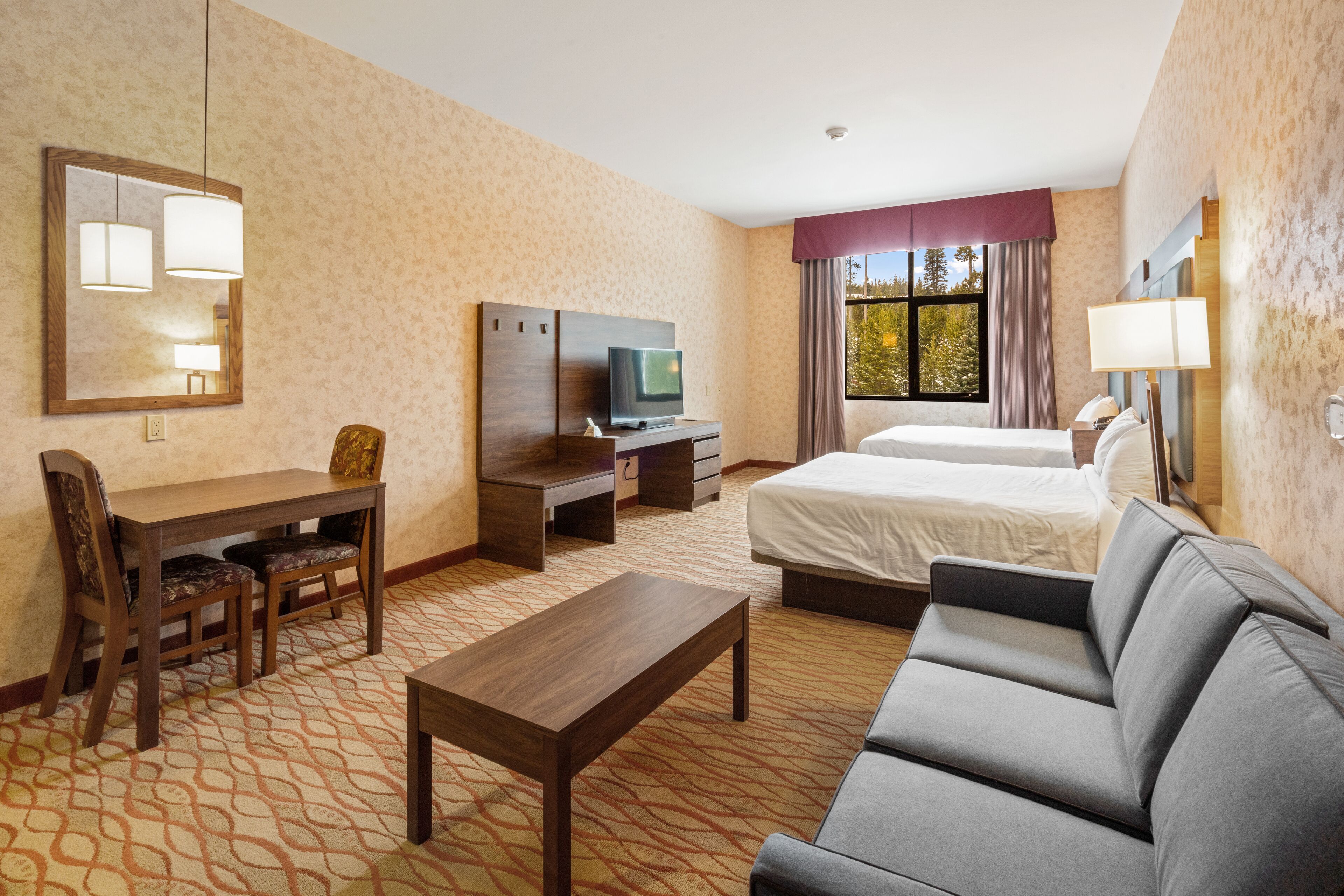 Una habitación de hotel con cama, sofá, escritorio y televisor.