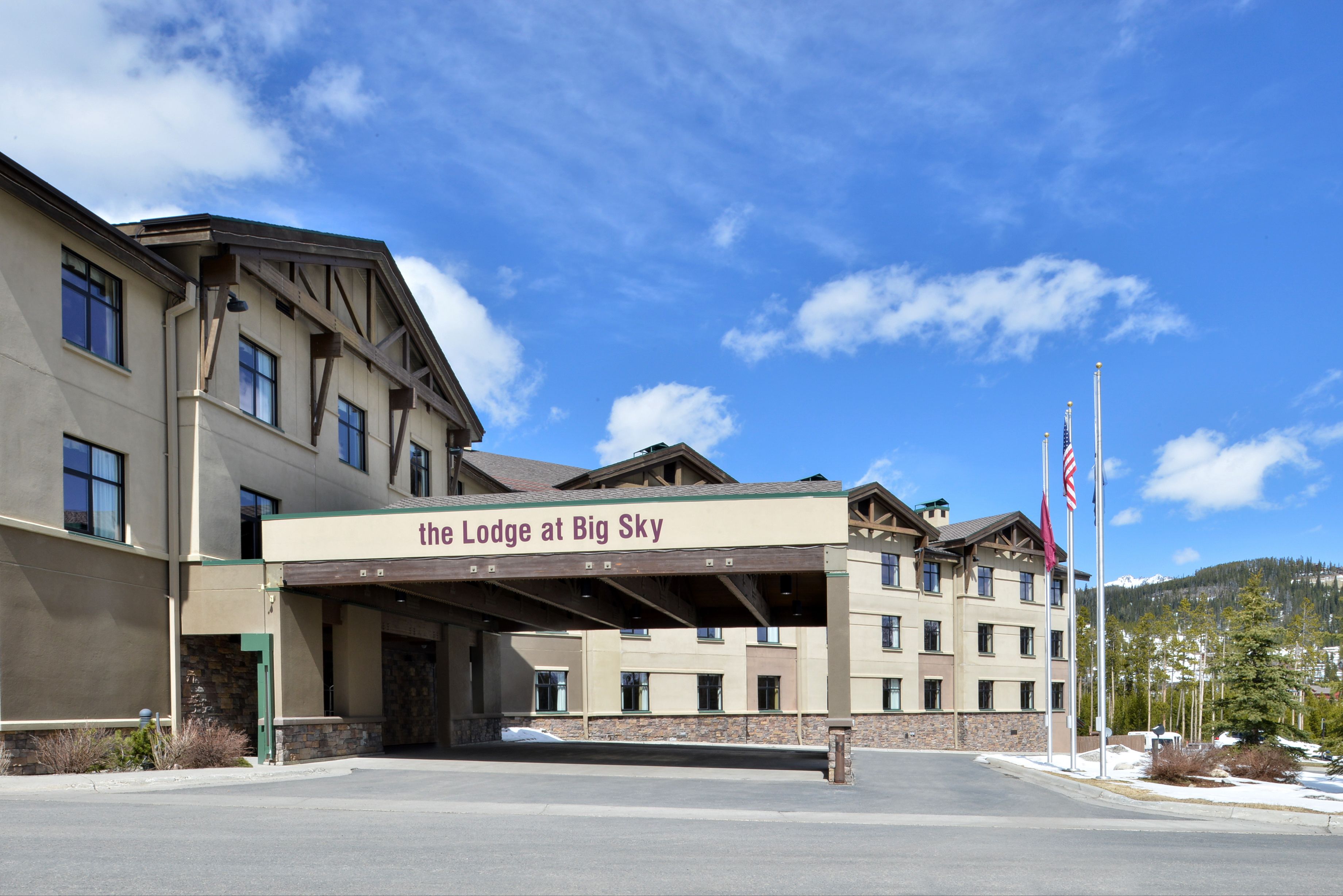 A multi-story hotel with a covered entrance and a sign reading "The Lodge at Big Sky".