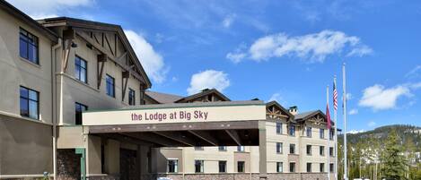 Un hotel de varios pisos con entrada cubierta y un cartel que dice "The Lodge at Big Sky".