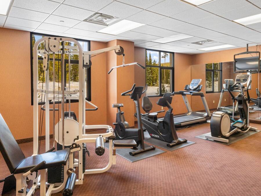 A gym with various exercise equipment, large windows, and a television.