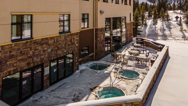 A hotel with a ski slope view, outdoor seating, and a pool area. - The Lodge at Big Sky (Big Sky)