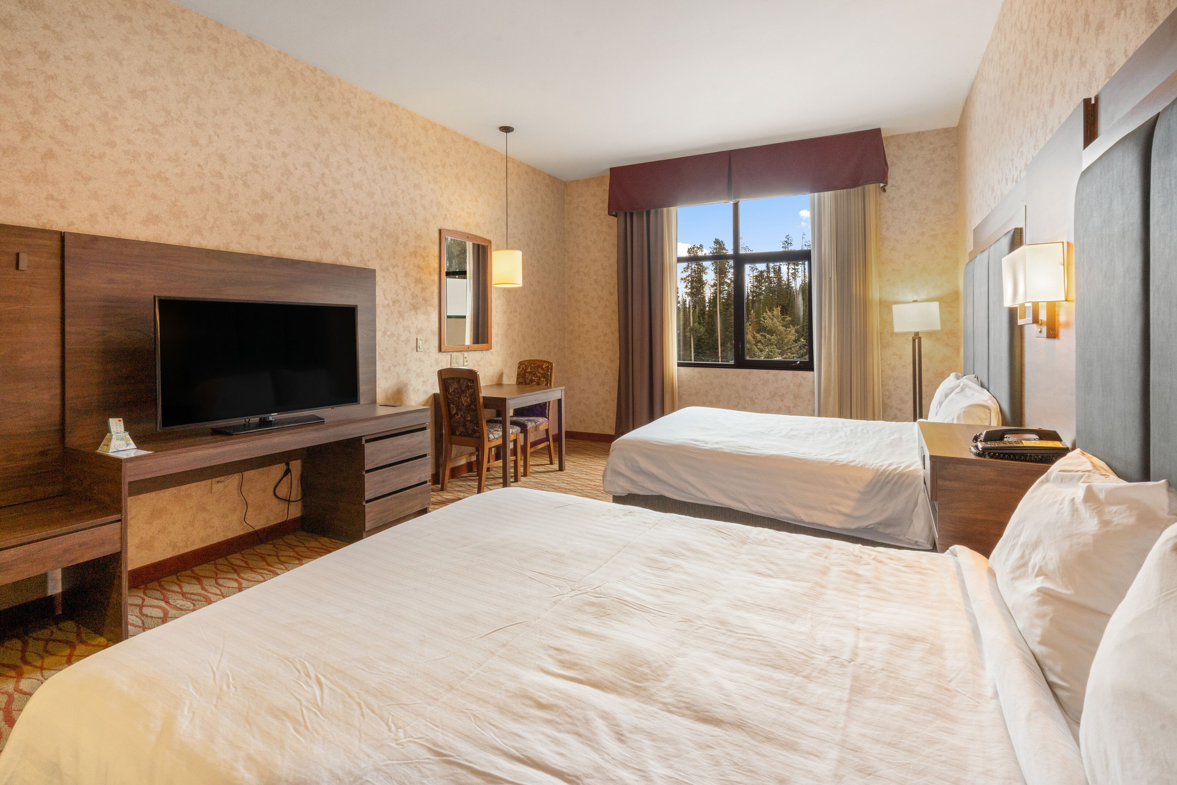 A hotel room with two beds, a TV, a desk, and a chair.