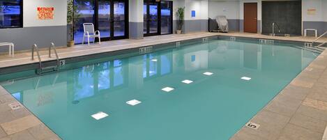 Ein Hallenbad mit klarem Wasser, Schwimmbahnen und Sicherheitsschildern.