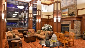 A spacious lobby with a fireplace, comfortable seating, and a large window overlooking the city. - The Lodge at Big Sky (Big Sky)