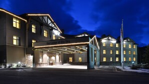 A hotel entrance with a covered walkway, a sign reading "The Lodge at Big Sky," and a flagpole with flags. - The Lodge at Big Sky (Big Sky)