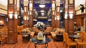 A lobby with wooden furniture, a central table with a sign, and a large window in the background. - The Lodge at Big Sky (Big Sky)