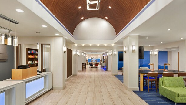 A hotel lobby with a reception desk, a dining area, and a seating area with a green chair. - Holiday Inn Express Hotel & Suites Mission-McAllen Area by IHG (Mission)