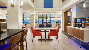 A modern dining area with a long table, red chairs, and a coffee station. - Holiday Inn Express Hotel & Suites Mission-McAllen Area by IHG (Mission)