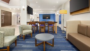 A hotel lobby with a round table, sofas, and a TV mounted on the wall. - Holiday Inn Express Hotel & Suites Mission-McAllen Area by IHG (Mission)