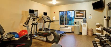A gym with cardio equipment, dumbbells, and a water dispenser.