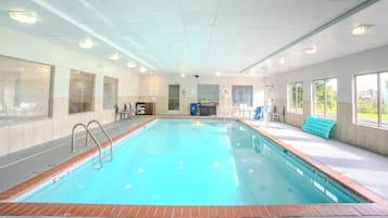 Una piscina interior con agua cristalina, un cartel de prohibición de saltos y un cartel con las normas de la piscina.